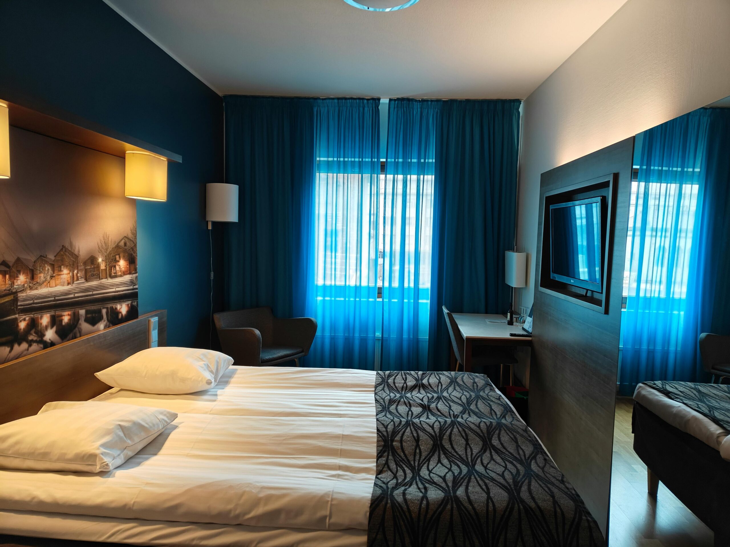 A stylish hotel room with blue curtains and modern decor, perfect for relaxation.